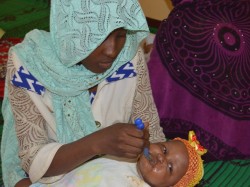 Ce bébé est jumelle. Sa jumelle dort pendant qu'une accompagnante du centre lui donne à manger